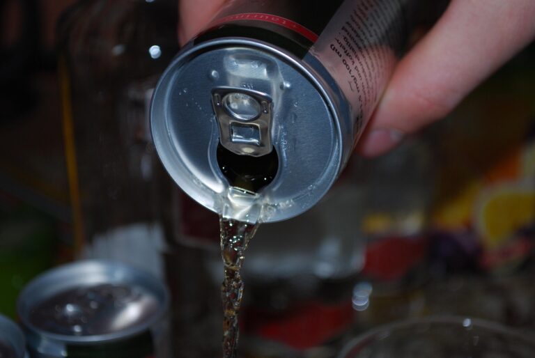 Une main verse le liquide contenu dans une canette de boisson énergisante avec le fond flou